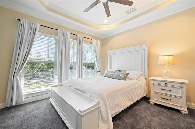 bedroom featuring multiple windows, visible vents, dark colored carpet, and a tray ceiling