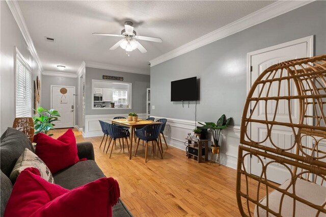 living room with ceiling fan, ornamental molding, and light hardwood / wood-style flooring