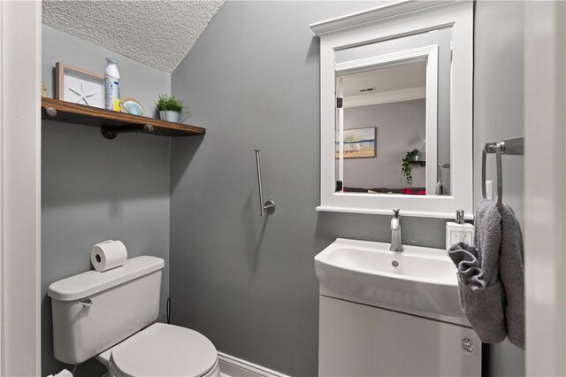 bathroom with crown molding, lofted ceiling, a textured ceiling, toilet, and vanity