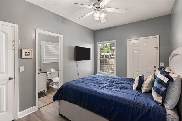 bedroom featuring ceiling fan, light hardwood / wood-style floors, a textured ceiling, and ensuite bath