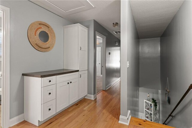 hallway featuring a textured ceiling and light hardwood / wood-style floors