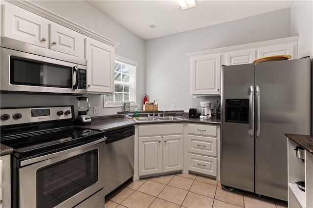 kitchen featuring light tile patterned flooring, white cabinetry, sink, and appliances with stainless steel finishes