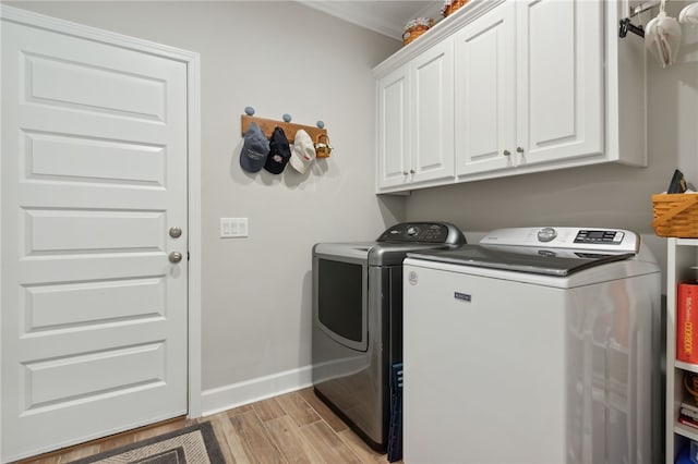 clothes washing area with washing machine and clothes dryer, cabinets, and light wood-type flooring