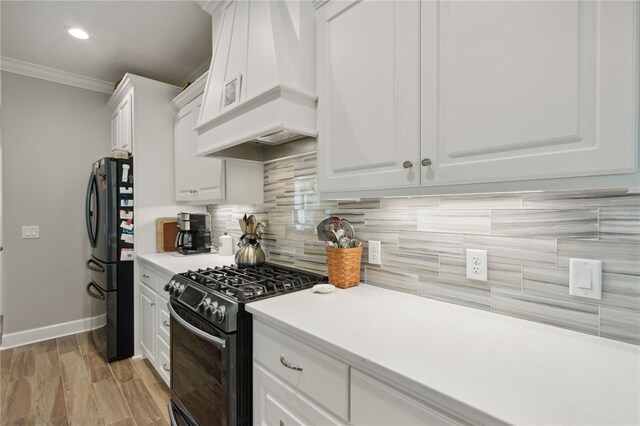 kitchen featuring decorative backsplash, ornamental molding, custom range hood, black appliances, and white cabinetry