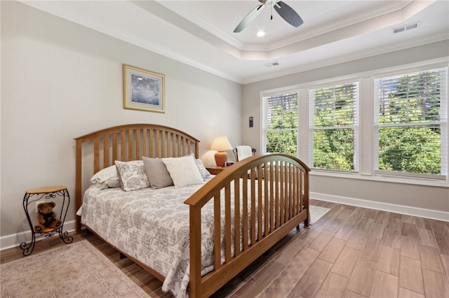 bedroom featuring ceiling fan, a raised ceiling, wood-type flooring, and crown molding