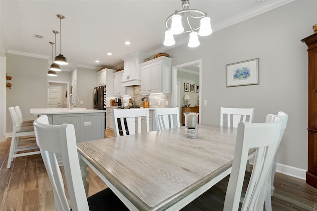 dining area with a chandelier, dark hardwood / wood-style flooring, crown molding, and sink