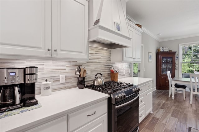 kitchen with backsplash, premium range hood, white cabinets, light hardwood / wood-style flooring, and gas stove