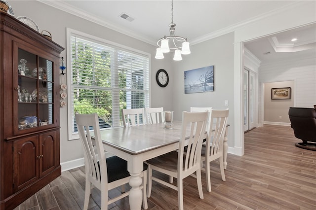 dining space with wood-type flooring, a notable chandelier, and ornamental molding