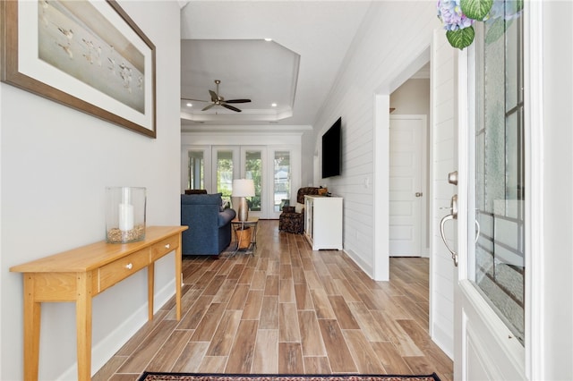 entrance foyer featuring french doors, light wood-type flooring, a tray ceiling, and ceiling fan