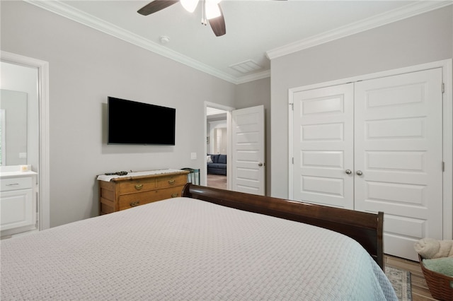 bedroom with crown molding, hardwood / wood-style flooring, ceiling fan, connected bathroom, and a closet