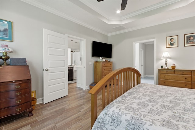 bedroom featuring ensuite bath, ceiling fan, a tray ceiling, hardwood / wood-style flooring, and ornamental molding