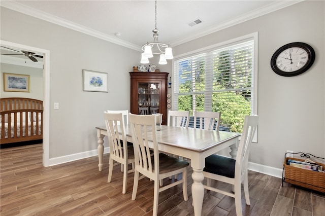 dining space featuring hardwood / wood-style floors, ceiling fan with notable chandelier, and crown molding