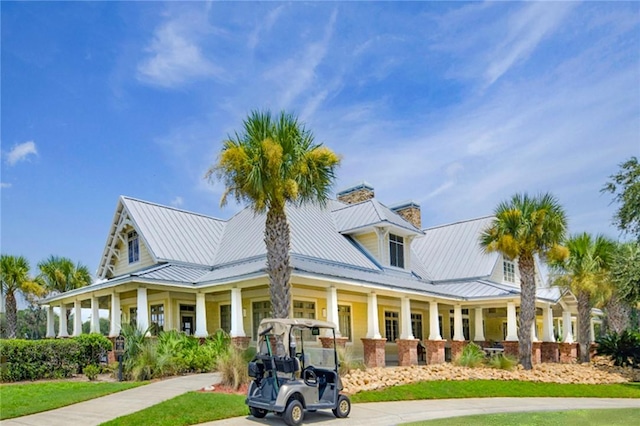 373 Harbour Island Cir, Waverly, GA 31565 - view of front facade with a porch, a chimney, a metal roof, and a front yard