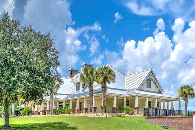 373 Harbour Island Cir, Waverly, GA 31565 - view of front of home featuring a porch, a front lawn, a chimney, and a metal roof