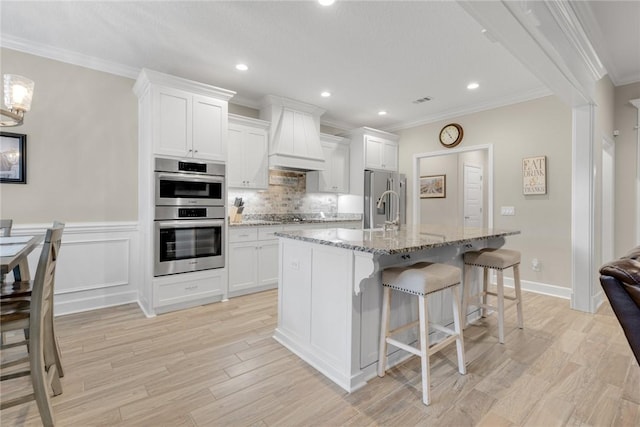 373 Harbour Island Cir, Waverly, GA 31565 - kitchen featuring stainless steel appliances, crown molding, custom range hood, a center island with sink, and a breakfast bar area