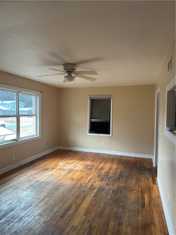 empty room with ceiling fan and dark wood-type flooring