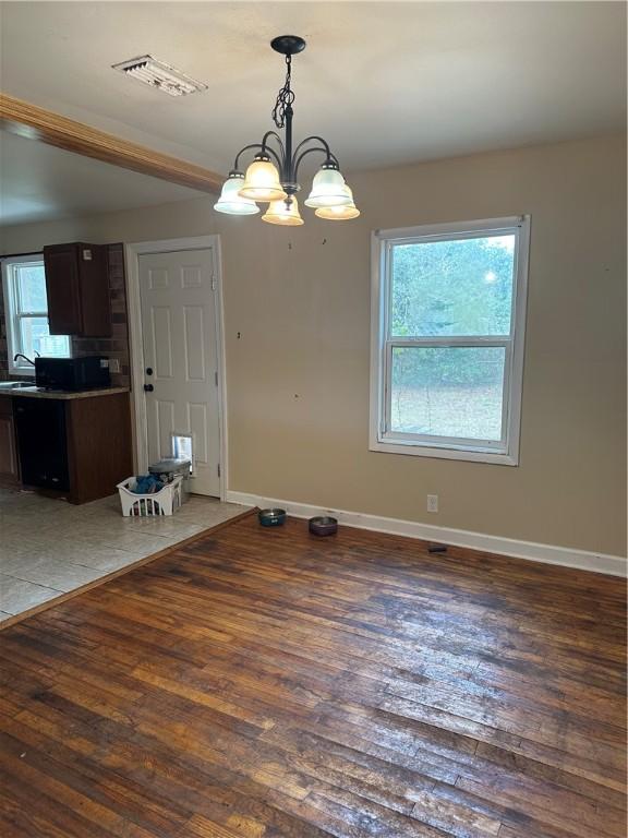 unfurnished dining area featuring sink, dark hardwood / wood-style floors, and a notable chandelier