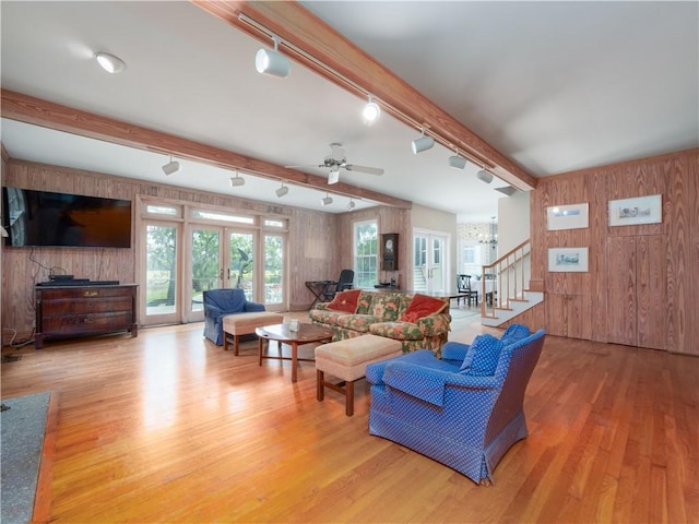 living area featuring wood walls, rail lighting, stairway, wood finished floors, and beam ceiling