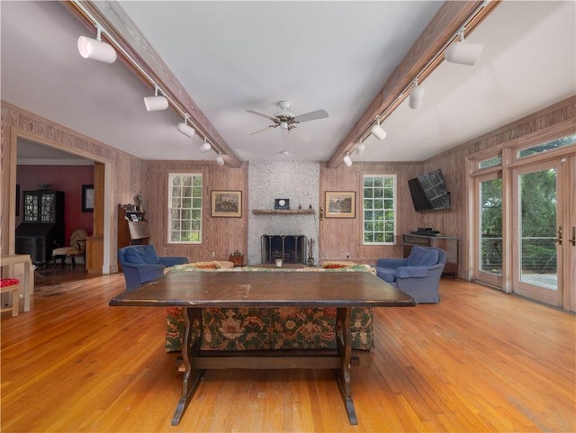 living room featuring track lighting, a large fireplace, wood-type flooring, a ceiling fan, and wood walls