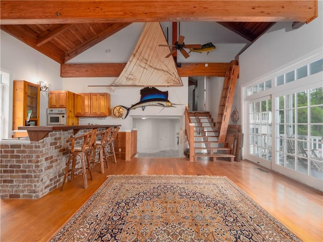 kitchen with high vaulted ceiling, wooden ceiling, light wood-type flooring, beamed ceiling, and ceiling fan