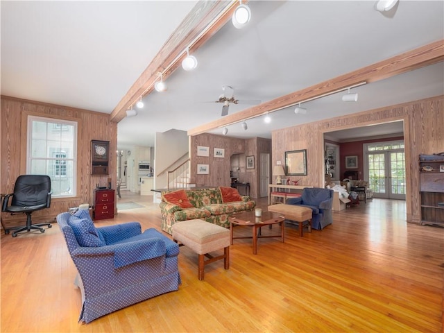 living room featuring track lighting, wood walls, stairway, light wood-style floors, and ceiling fan