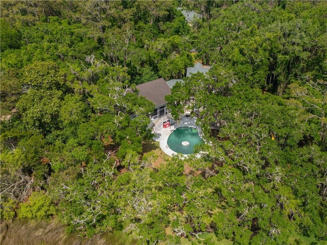 aerial view of property and surrounding area featuring a pool and a forest