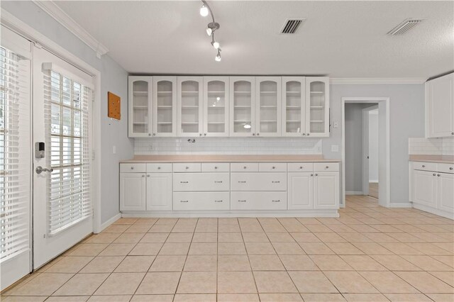 701 Third Ave, Saint Simons Island, GA 31522 - kitchen with light countertops, visible vents, decorative backsplash, and glass insert cabinets