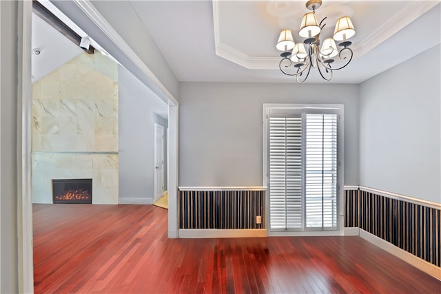 104 Cay Trce, Brunswick, GA 31525 - spare room featuring wood-type flooring, a chandelier, a tray ceiling, a tile fireplace, and crown molding