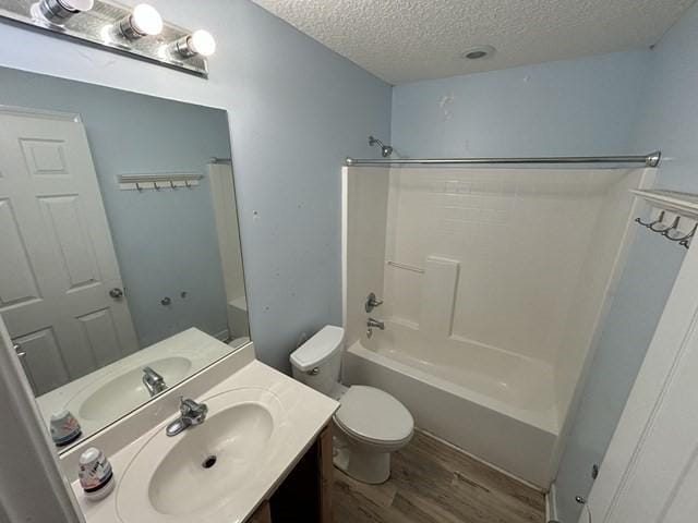 full bathroom with vanity, bathtub / shower combination, toilet, a textured ceiling, and wood-type flooring