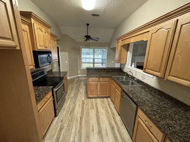 kitchen with ceiling fan, sink, stainless steel appliances, a textured ceiling, and vaulted ceiling