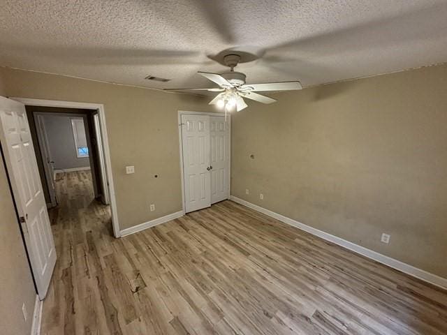 unfurnished bedroom with ceiling fan, a textured ceiling, and light hardwood / wood-style flooring