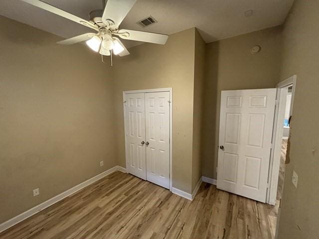 unfurnished bedroom with a towering ceiling, a closet, light hardwood / wood-style flooring, and ceiling fan