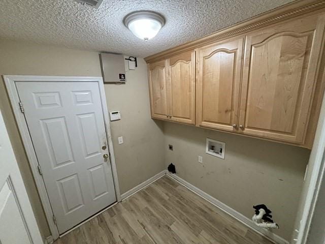 washroom featuring cabinets, washer hookup, a textured ceiling, hookup for an electric dryer, and light hardwood / wood-style floors