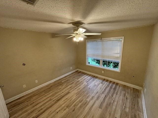 spare room with ceiling fan, wood-type flooring, and a textured ceiling