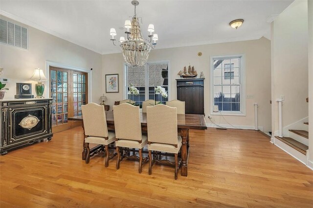 dining area with crown molding, french doors, a notable chandelier, and light wood-type flooring