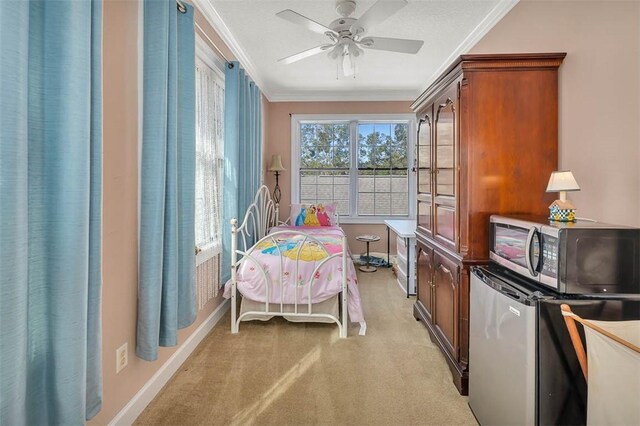 bedroom featuring stainless steel refrigerator, ceiling fan, crown molding, and light carpet