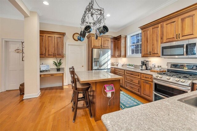 kitchen with a kitchen island, stainless steel appliances, decorative light fixtures, and light hardwood / wood-style floors