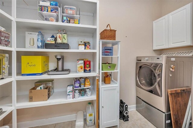 laundry area with washing machine and dryer, light tile patterned floors, and cabinets