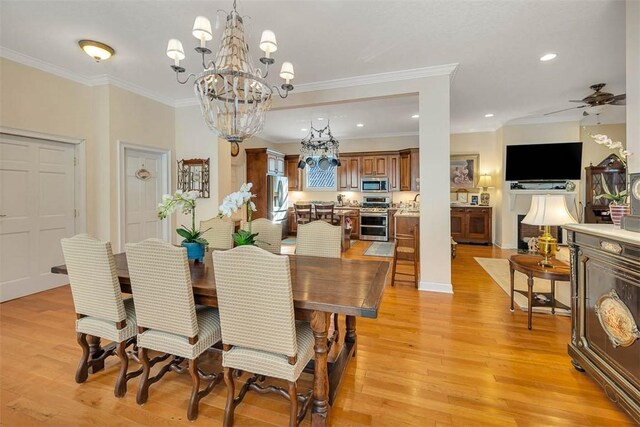 dining space featuring ceiling fan with notable chandelier, ornamental molding, and light hardwood / wood-style flooring