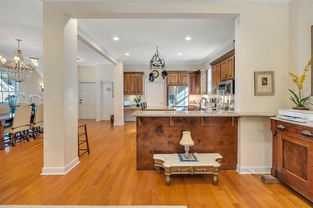 kitchen with a kitchen breakfast bar, kitchen peninsula, stainless steel appliances, and light wood-type flooring