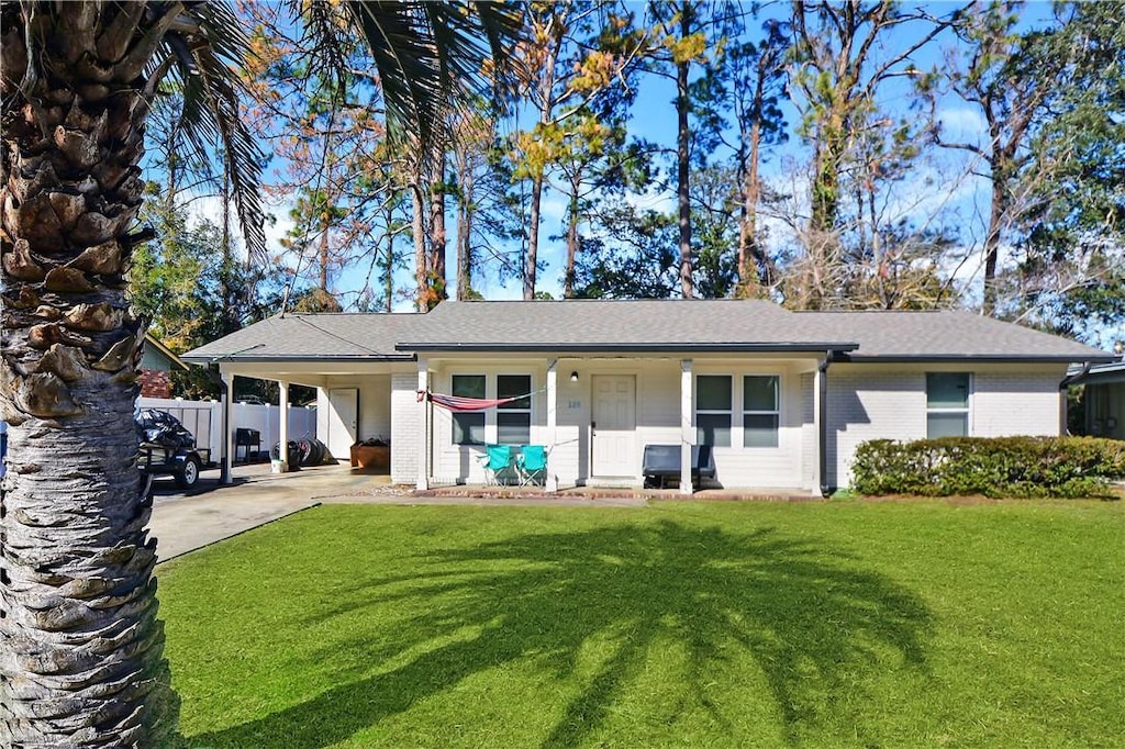 back of house featuring brick siding, a yard, a carport, and concrete driveway