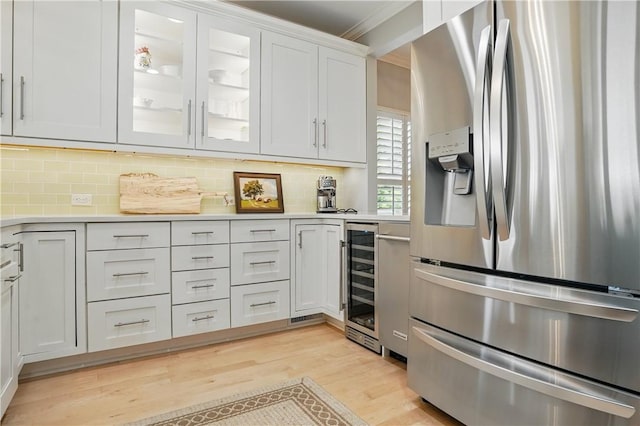 206 Dunbar Dr, Saint Simons Island, GA 31522 - kitchen featuring stainless steel fridge with ice dispenser, beverage cooler, light countertops, light wood finished floors, and tasteful backsplash