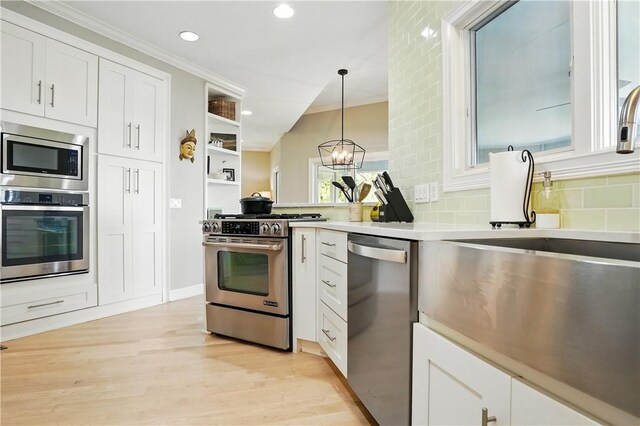 kitchen with decorative backsplash, white cabinetry, light wood-style flooring, decorative light fixtures, and stainless steel appliances