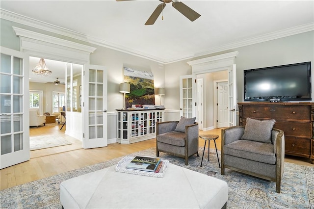 living area with ornamental molding, a ceiling fan, french doors, and wood finished floors