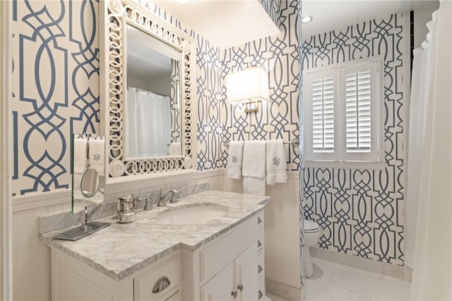 full bathroom featuring vanity, toilet, wallpapered walls, and marble finish floor