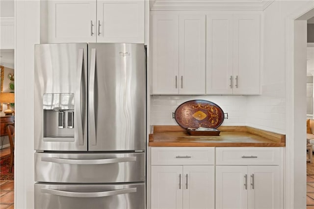 kitchen with white cabinets, backsplash, stainless steel refrigerator with ice dispenser, and butcher block countertops