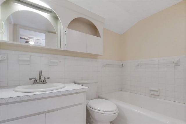 bathroom with ceiling fan, a tub to relax in, toilet, vanity, and tile walls