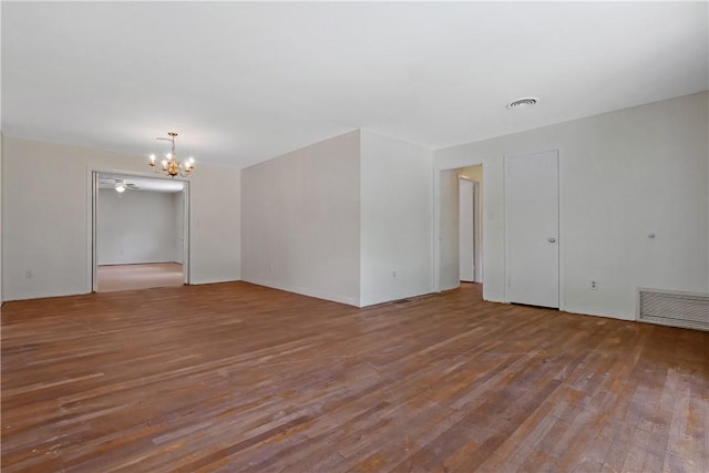 empty room with wood-type flooring and a chandelier