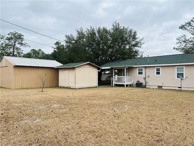 rear view of property featuring cooling unit and a storage shed