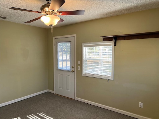 entryway featuring a barn door, ceiling fan, a textured ceiling, and dark colored carpet